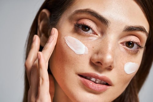 Woman applying moisturiser to her face as part of a simple skincare routine